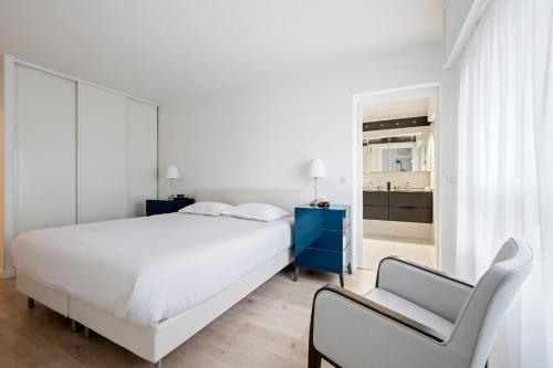 ein weißes Schlafzimmer mit einem großen Bett und einem Stuhl in der Unterkunft Veeve - Abstract Allure in Paris