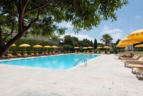 una gran piscina con sillas y sombrillas en Relais Casina Copini, en Spongano
