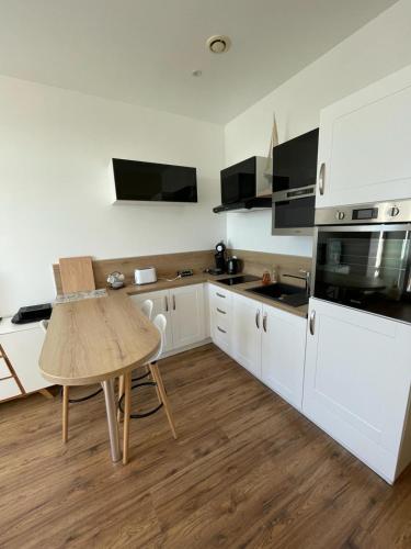 une cuisine avec des armoires blanches et une table en bois dans l'établissement La mer à perte de vue, Wimereux, côte d opale, à Wimereux