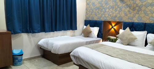 2 letti in camera d'albergo con tende blu di Hotel Gurukul INN a Ahmedabad