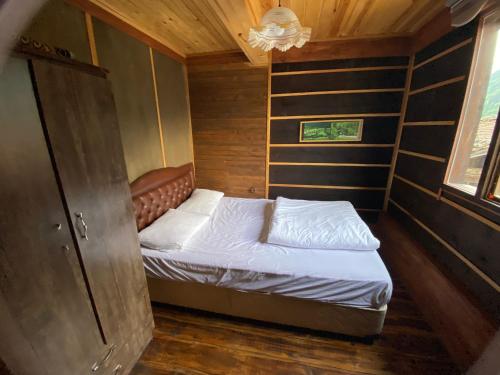 WOODEN OCHENA in UZUNGÖL في جايكارا: غرفة نوم صغيرة مع سرير في غرفة خشبية
