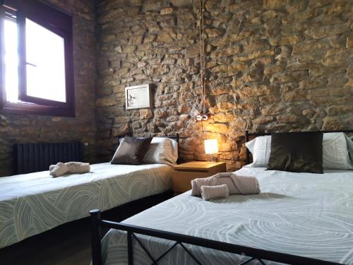 2 camas en una habitación con una pared de piedra en Casa Fonset, en Àger