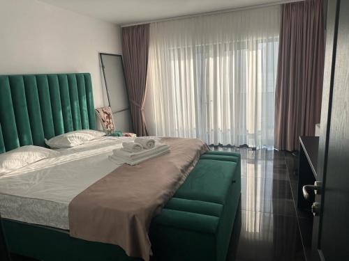 a bedroom with a large bed with a green headboard at Pensiunea PHILIA in Dubova