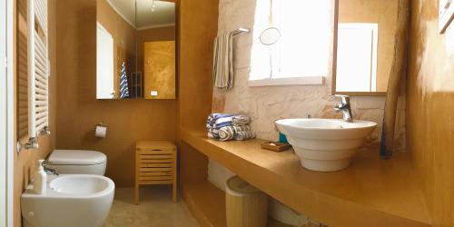 een badkamer met een wastafel, een toilet en een spiegel bij trullo contemporaneo in Serranova