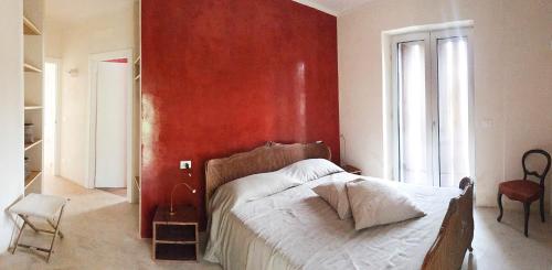 a bedroom with a red wall and a bed at trullo contemporaneo in Serranova