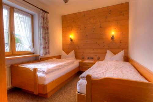 - 2 lits dans une chambre dotée de murs en bois dans l'établissement Gästehaus Manfred, à Mittenwald