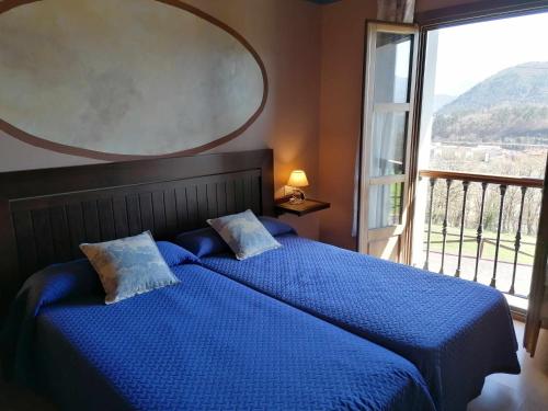 2 camas azules en un dormitorio con ventana grande en La Quintana de Villar, en Arriondas