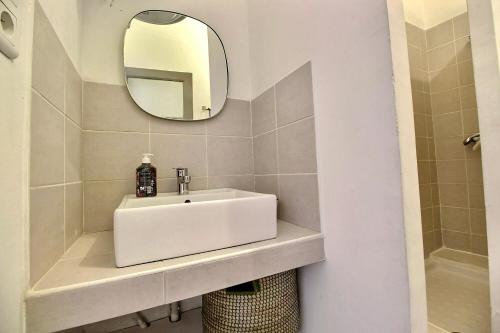 een badkamer met een witte wastafel en een spiegel bij SC Collection-Spacieux & Atypique au Panier in Marseille