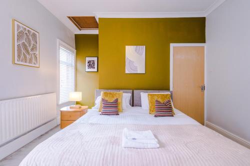 una camera da letto con un grande letto bianco e pareti gialle di Queens Avenue - Central Chester Home - Sleeps 9 a Chester