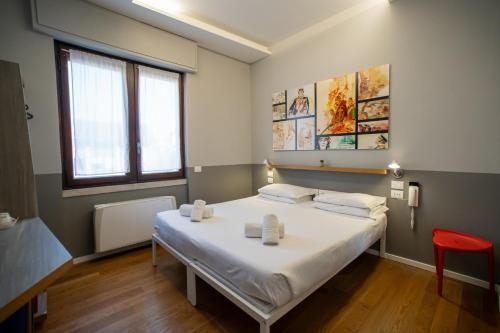 a bedroom with a large white bed with a red chair at Babila Hostel & Bistrot in Milan