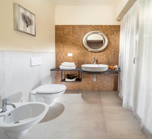 y baño con 2 aseos, lavamanos y espejo. en Hotel Alba, en Misano Adriatico