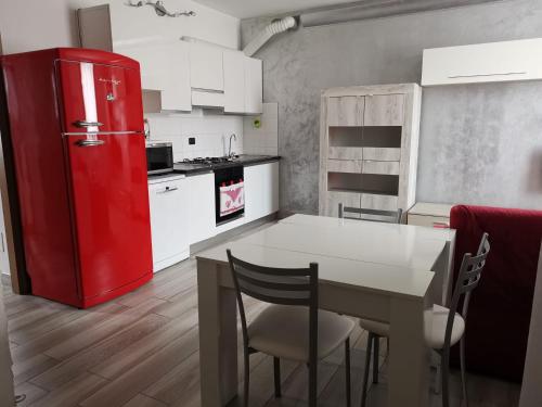 eine Küche mit einem roten Kühlschrank und einem Tisch in der Unterkunft Bomboniera Milano zona RHO FIERA - Bilocale 70mq in Senago