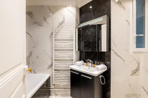 une salle de bain en noir et blanc avec un lavabo et un miroir dans l'établissement Veeve - Timeless Majesty, à Paris