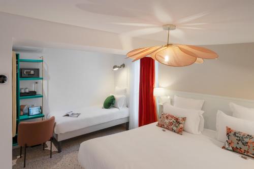 una camera d'albergo con 2 letti e una scrivania di Trendy Canettes Hotel a Parigi