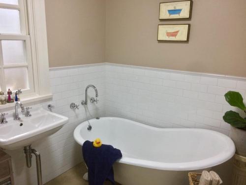 uma casa de banho com uma banheira e um lavatório em Bundanoon Bijou Southern Highlands Accommodation em Bundanoon