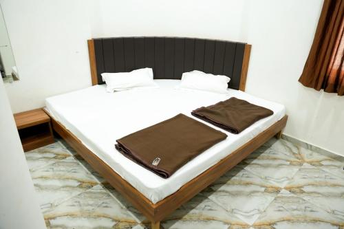 uma cama com lençóis brancos e um cobertor castanho em Hotel Aaram Kalupur em Ahmedabad