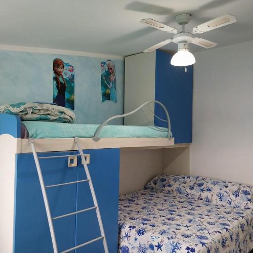 a bedroom with two bunk beds and a ceiling fan at Appartamento da alessandra in Torvaianica