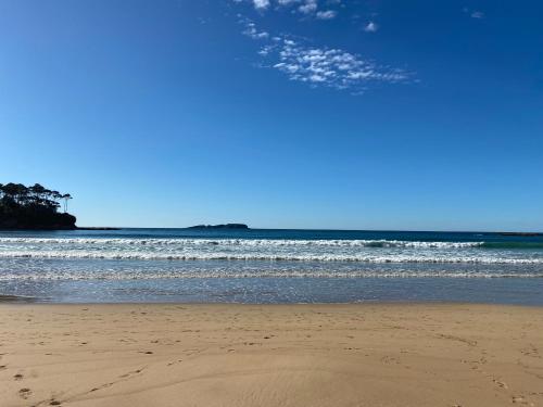 a sandy beach with the ocean in the background at A Sanctuary at Denhams - Family & Pooch Friendly in Surf Beach