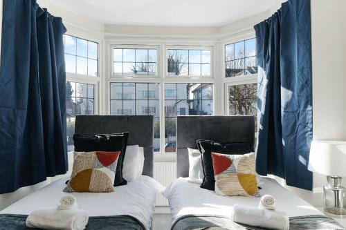 two beds in a room with blue curtains at Spacious house in Wembley - Garden in London