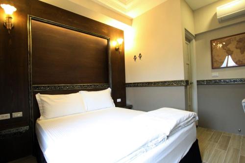 a bedroom with a large white bed with a wooden headboard at Fardo Homestay in Hualien City