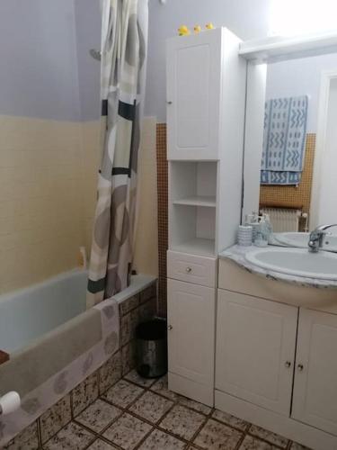 une salle de bain avec un lavabo et un rideau de douche dans l'établissement Appartement Corail, vue plongeante sur la mer, à Fréjus