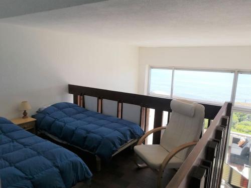 une chambre avec un lit, une chaise et une fenêtre dans l'établissement Appartement Corail, vue plongeante sur la mer, à Fréjus