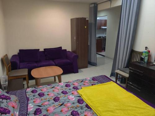 ein Wohnzimmer mit einem lila Sofa und einem Bett in der Unterkunft Lovely 2Bhk Family Apartment in Ajman in Al Ḩamīdīyah