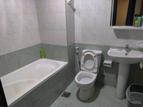 a bathroom with a tub and a toilet and a sink at Lovely 2Bhk Family Apartment in Ajman in Al Ḩamīdīyah