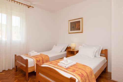 twee bedden in een kamer met witte muren bij Apartments Stone garden - cosy and comfy in Supetar