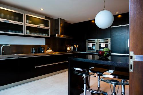 a kitchen with black cabinets and a bar with stools at Casa da Barra in Vila Nova de Gaia