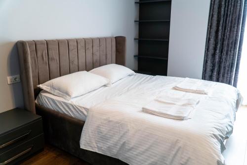 un letto con lenzuola bianche e due asciugamani sopra di Signature apartment 5 a Tirana
