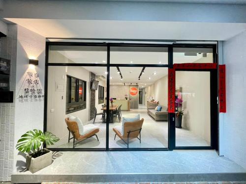 a living room with glass doors and chairs at Shuntai Inn in Fengshan