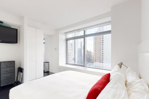 a bedroom with a white bed and a large window at Blueground Tribeca roof deck nr WTC NYC-1377 in New York