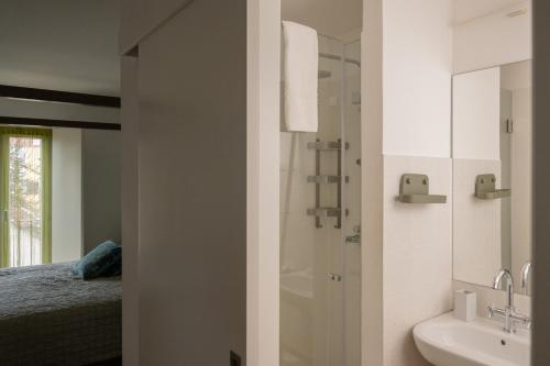 a bathroom with a shower and a sink next to a bed at Tings Lisbon in Lisbon