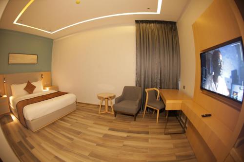 a hotel room with a bed and a desk and a tv at LIMERIDGE SIGNATURE HOTEL in Ikeja