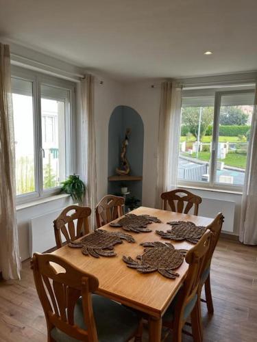 - une table en bois dans une chambre avec des chaises et des fenêtres dans l'établissement La Maison Blue, à Outreau