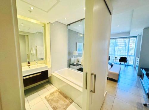 a bathroom with a bath tub and a bedroom at Love Luxe @ Sandton skye in Johannesburg