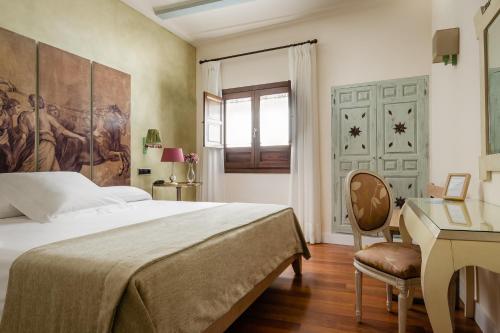 een slaapkamer met een bed en een bureau bij YIT La Casona del Arco in Baeza