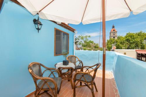 a table and chairs on a balcony with a clock tower at Old Town Roloi House in Rhodes Town