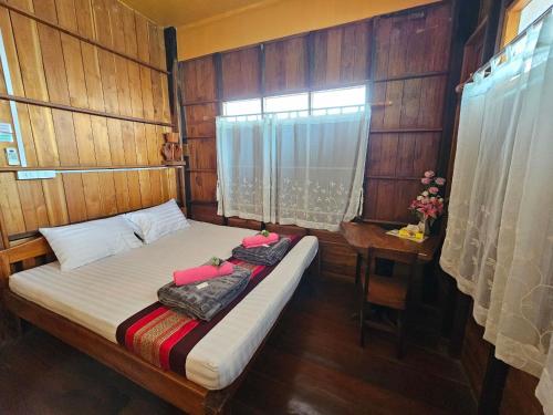 a bed in a room with a window and a table at บ้านเรือนไทยมะลิเมืองเก่า in Sukhothai