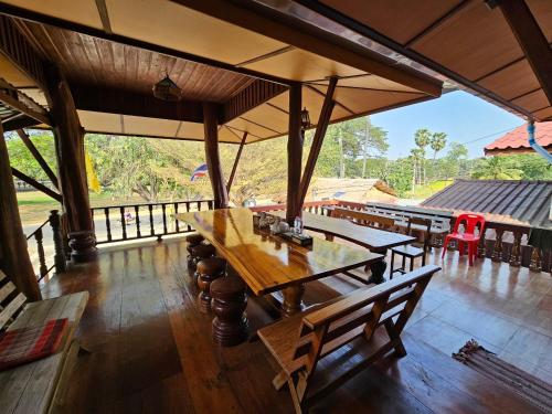 a dining room with a table and chairs and a view at บ้านเรือนไทยมะลิเมืองเก่า in Sukhothai
