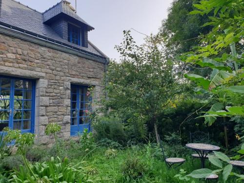 een oud stenen huis met blauwe ramen en een tuin bij la balinade in Riantec