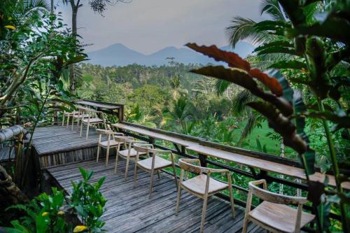 a row of chairs sitting on a wooden deck at Abing Dalem - Villa Manggis in Tabanan