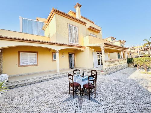 a table with two chairs in front of a house at Holiday House Praia D Ana in Lagos