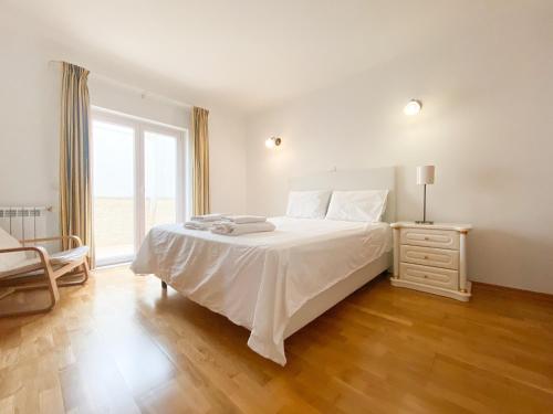 a white bedroom with a bed and a window at Holiday House Praia D Ana in Lagos