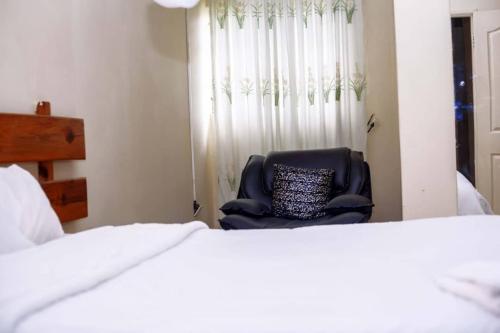 a chair in a bedroom with a window and a bed at White Lotus Lodges Katete in Chongwe