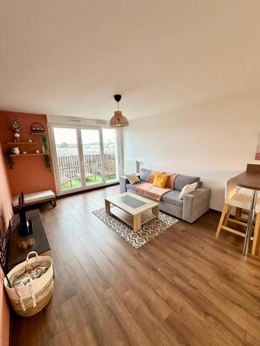 un salon avec un canapé et une table dans l'établissement Appartement chaleureux - Meaux, à Meaux