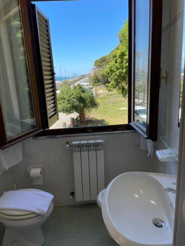 uma casa de banho com um lavatório, um WC e uma janela. em Hotel Eden em Follonica