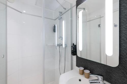 ein weißes Badezimmer mit einem Waschbecken und einem Spiegel in der Unterkunft ibis Paris Gare du Nord TGV in Paris