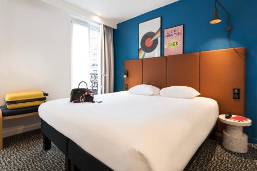 ein Hotelzimmer mit einem großen Bett mit blauen Wänden in der Unterkunft ibis Paris Gare du Nord TGV in Paris